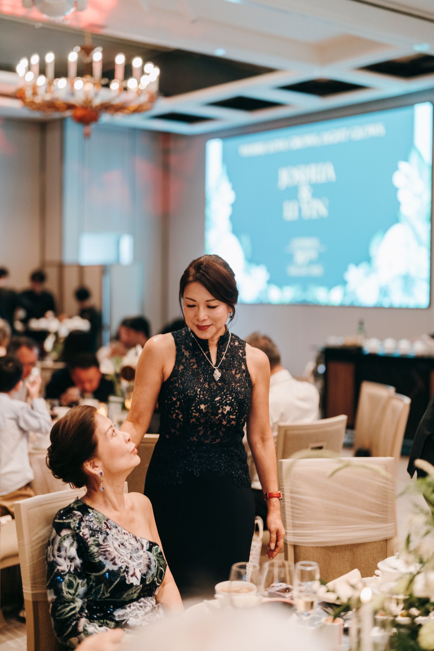 Formal dinner event with elegant black and white attire under crystal chandeliers.