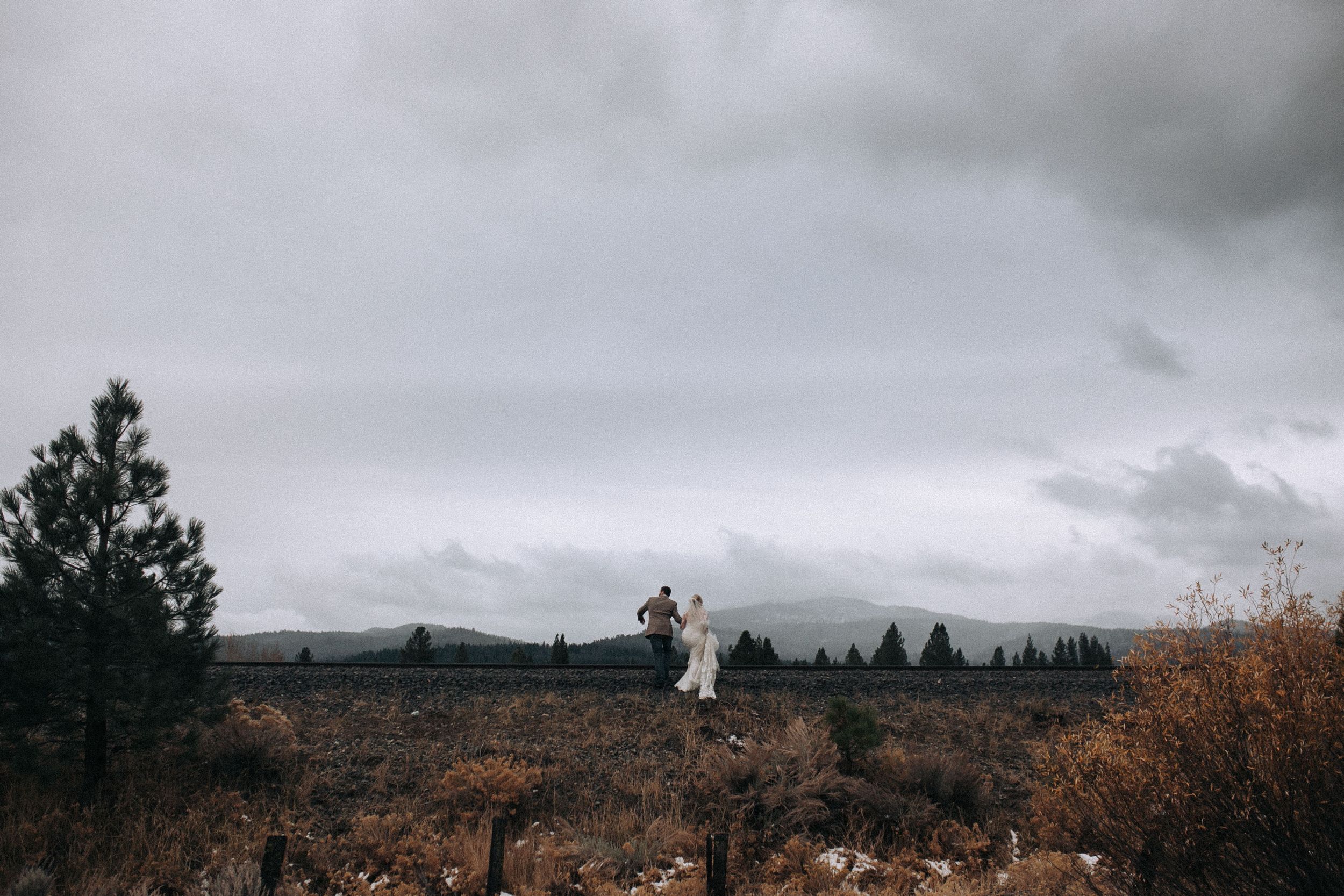 Bride and groom walking together in a wide-open Idaho field at sunset
