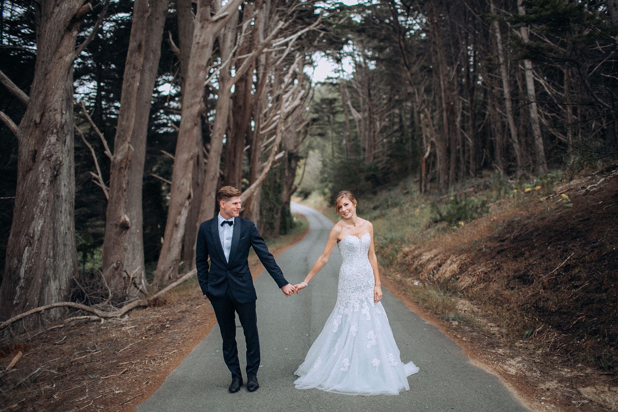 Bride and groom walking along the coast during their seaside wedding
