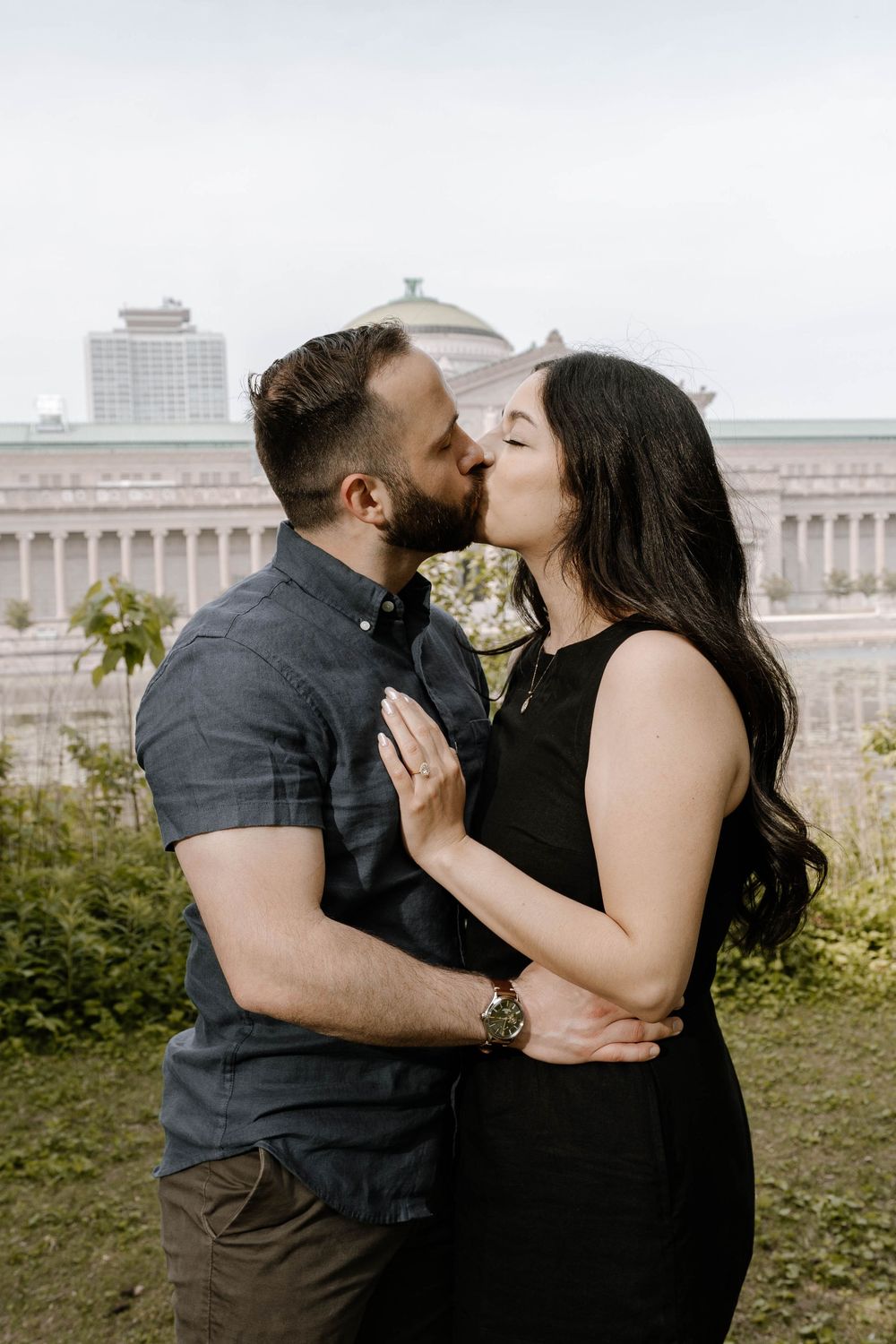 A romantic couple shares tender kisses in a series of four photos taken outdoors with a historic building in the background.