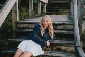 Person sitting on rustic wooden steps in casual outdoor setting.