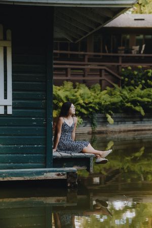 Person sitting on wooden dock over tranquil pond with reflections in the water.
