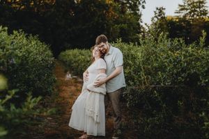 Couple embracing in a lush garden setting surrounded by green foliage.