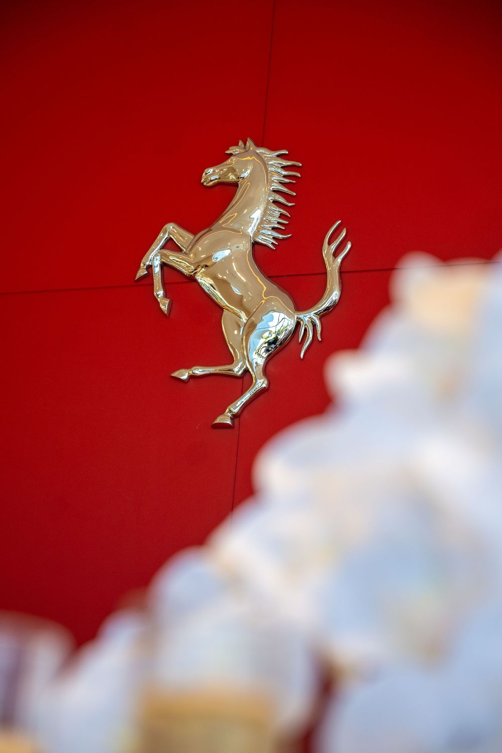 Ferrari prancing horse emblem shown in gold against a vibrant red background.