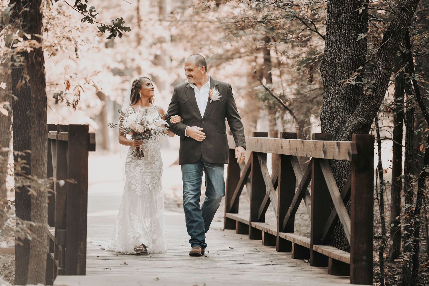 the bride and her dad walking across the rustic bridge at whispering oaks