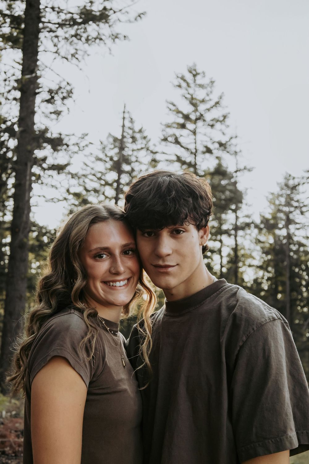 Couple in casual wear sharing intimate moment in forest setting.