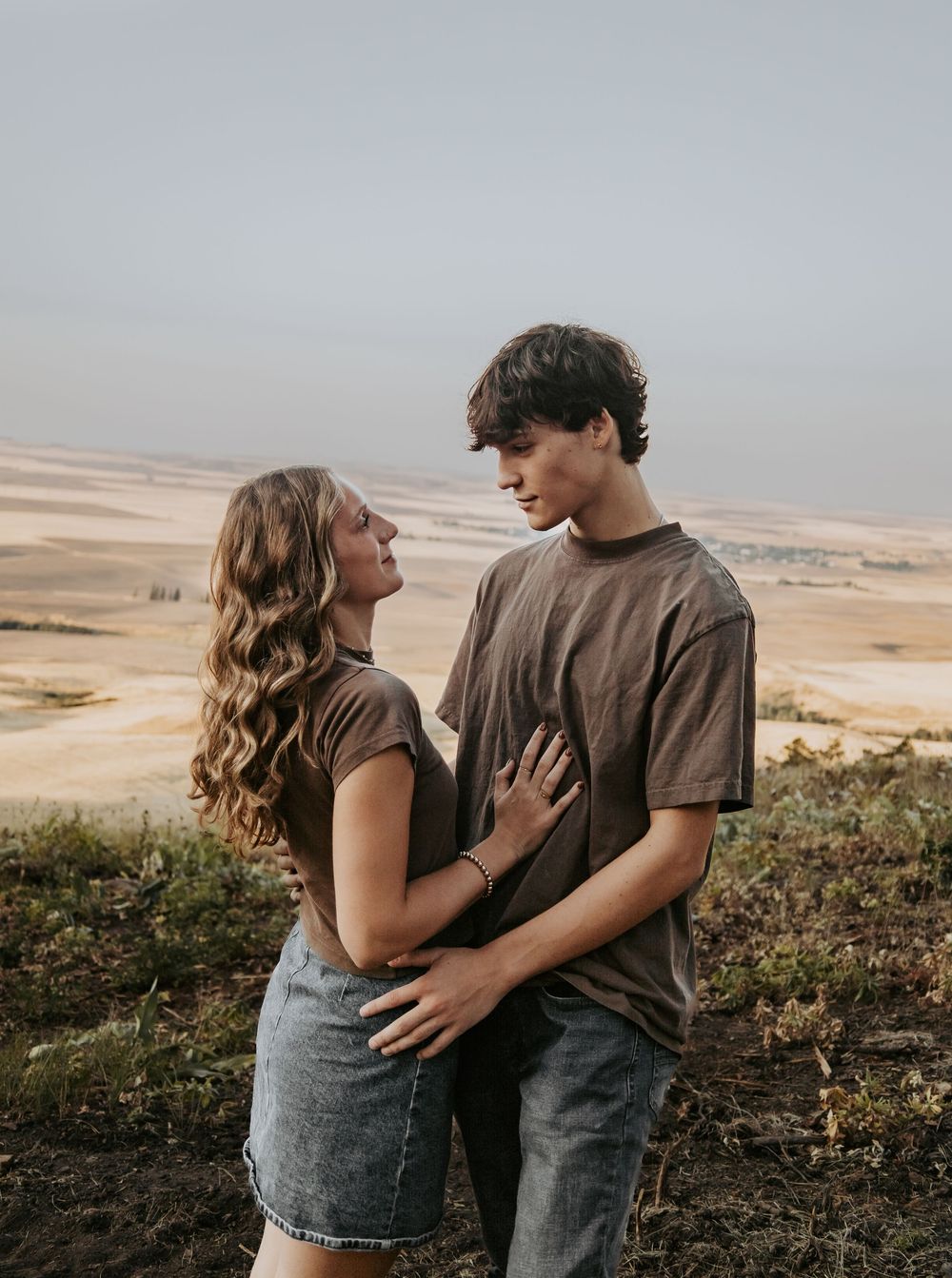 A couple embraces against a desert landscape backdrop during golden hour.