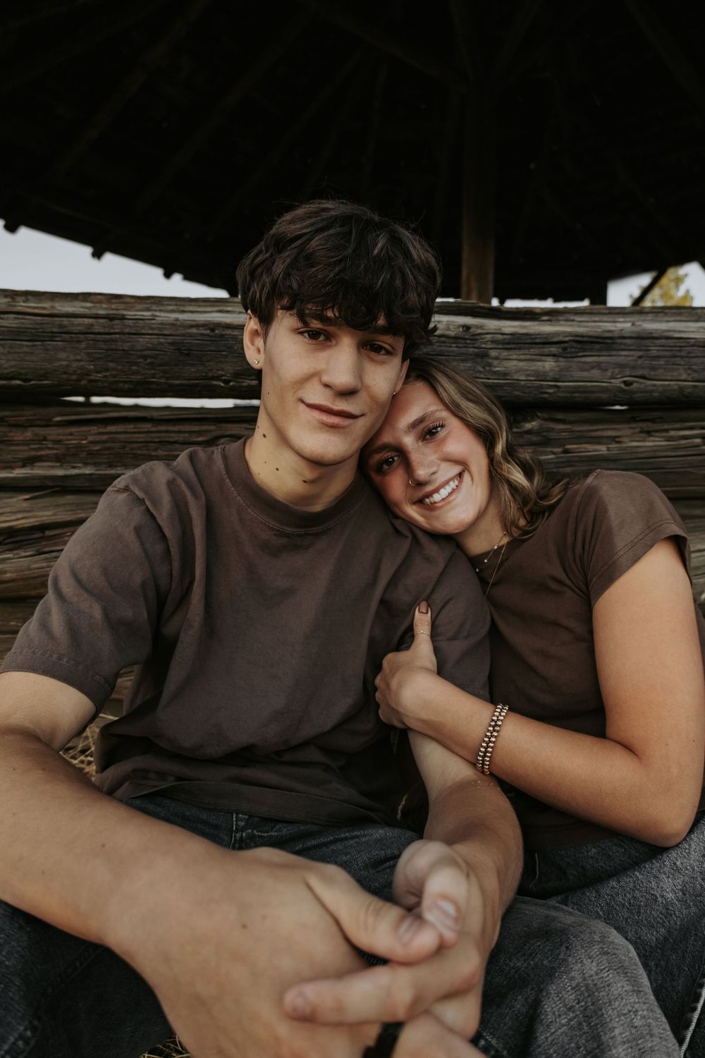 A couple shares an intimate moment while sitting together on a wooden bench.