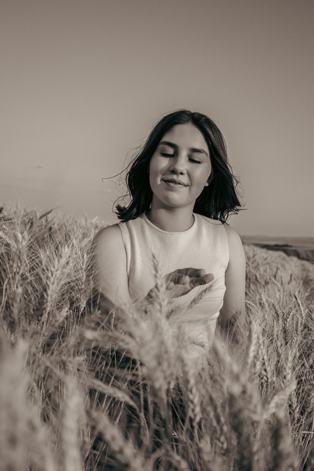 Black and white portraits in wheat field wearing light colored top with dreamy atmosphere.