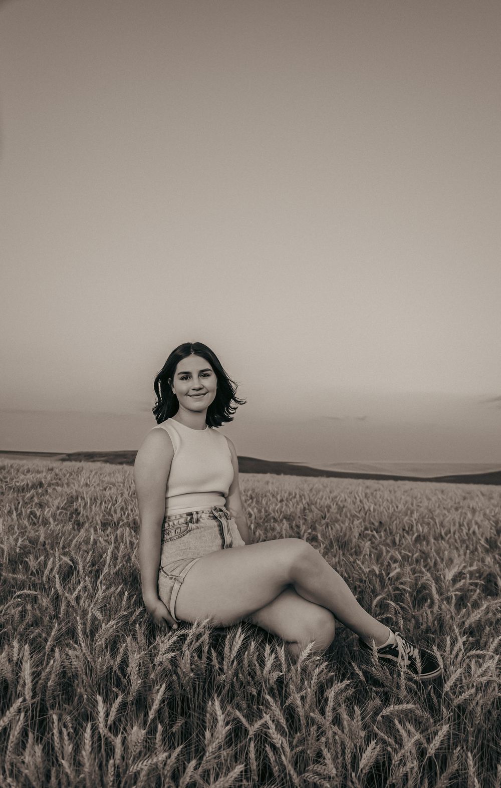 Monochrome portraits in wheat field showing casual poses in light summer outfit.