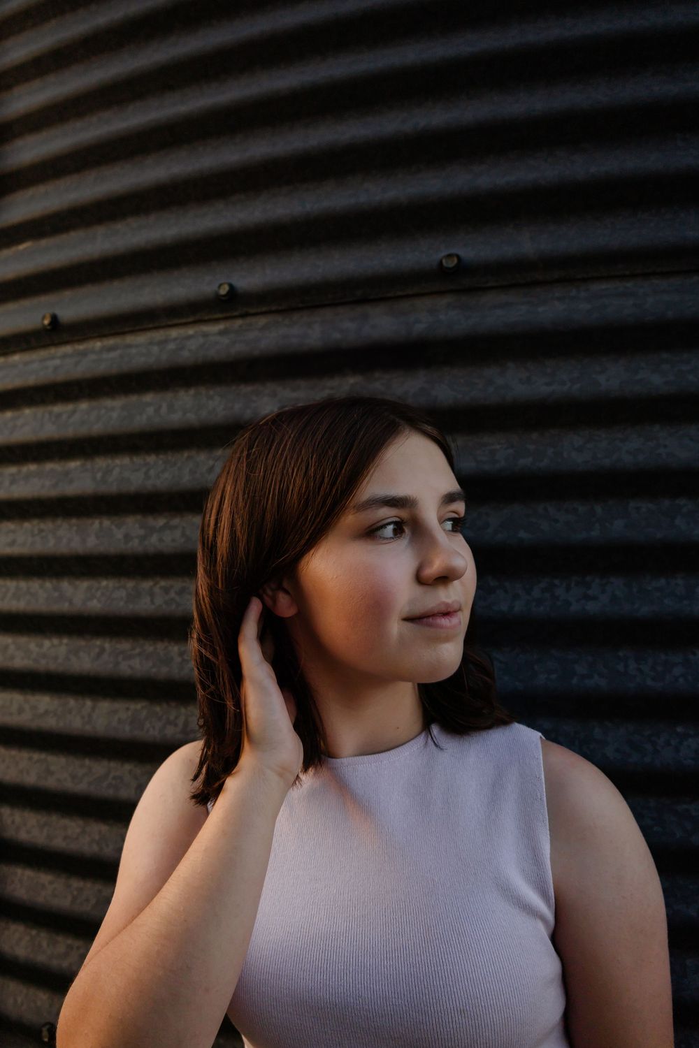 Portrait against corrugated metal wall in dramatic lighting.