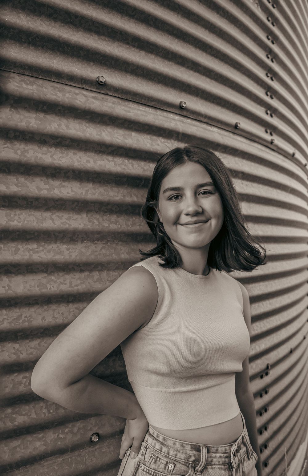 Casual pose against industrial corrugated wall backdrop.