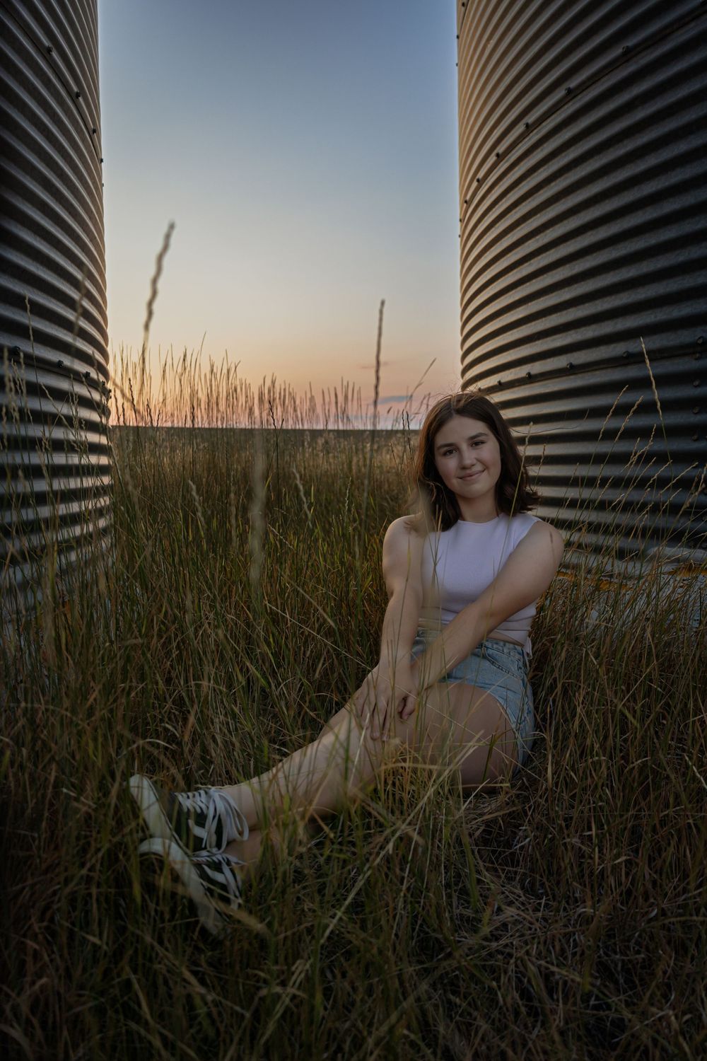Sunset portrait by grain silo in tall grass.