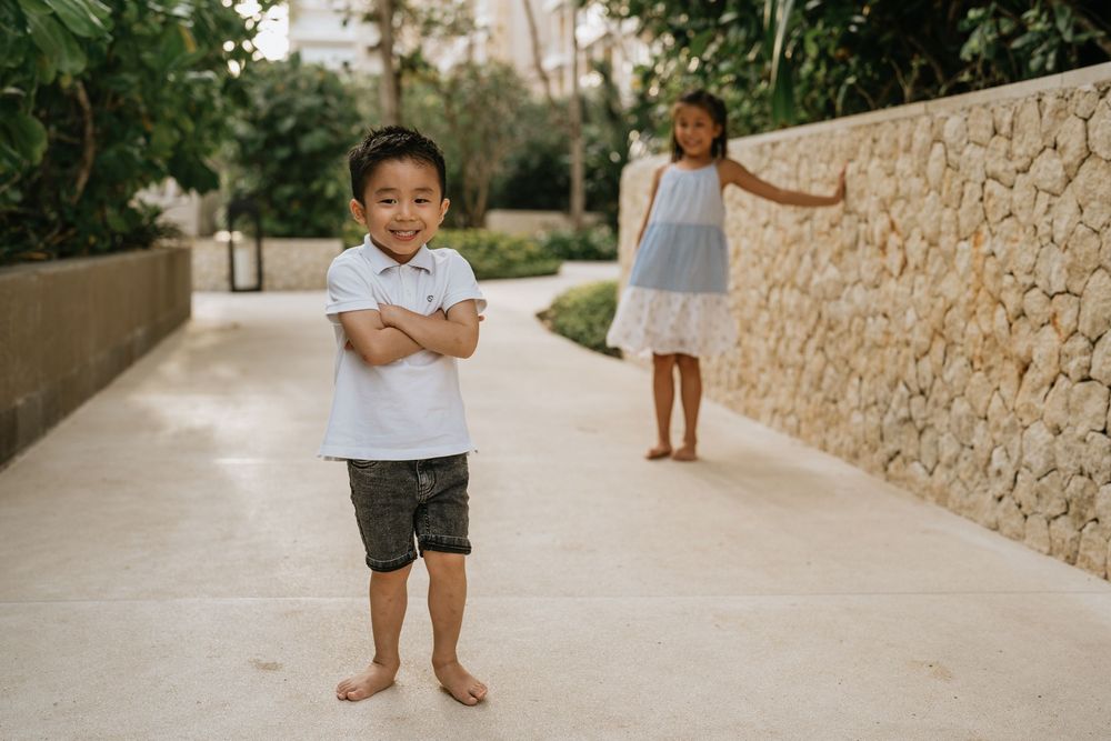 Children play and run along a stone pathway at a tropical resort.