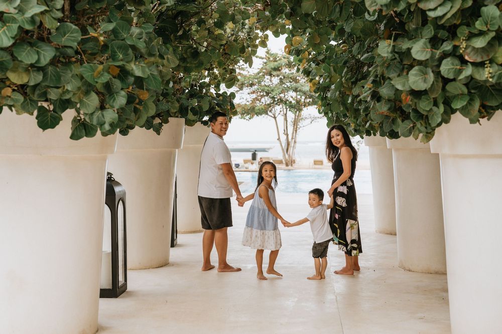 Family walks through a covered walkway with hanging plants at a resort.