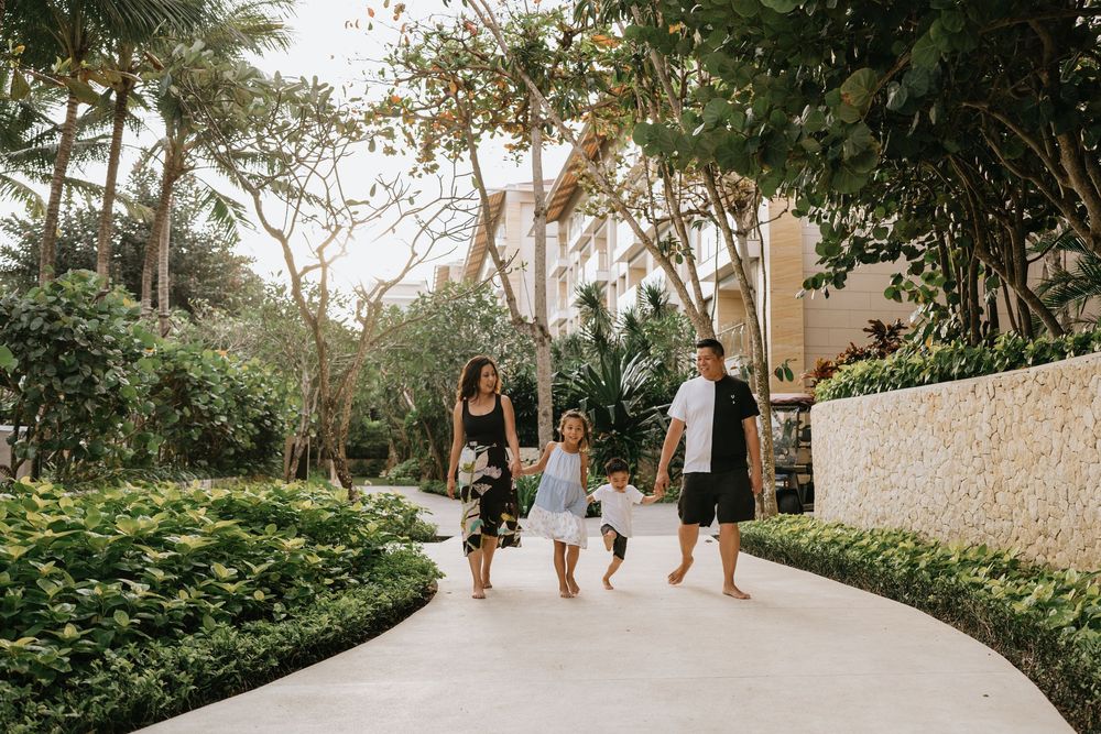 Family walking together along a lush tropical garden pathway.