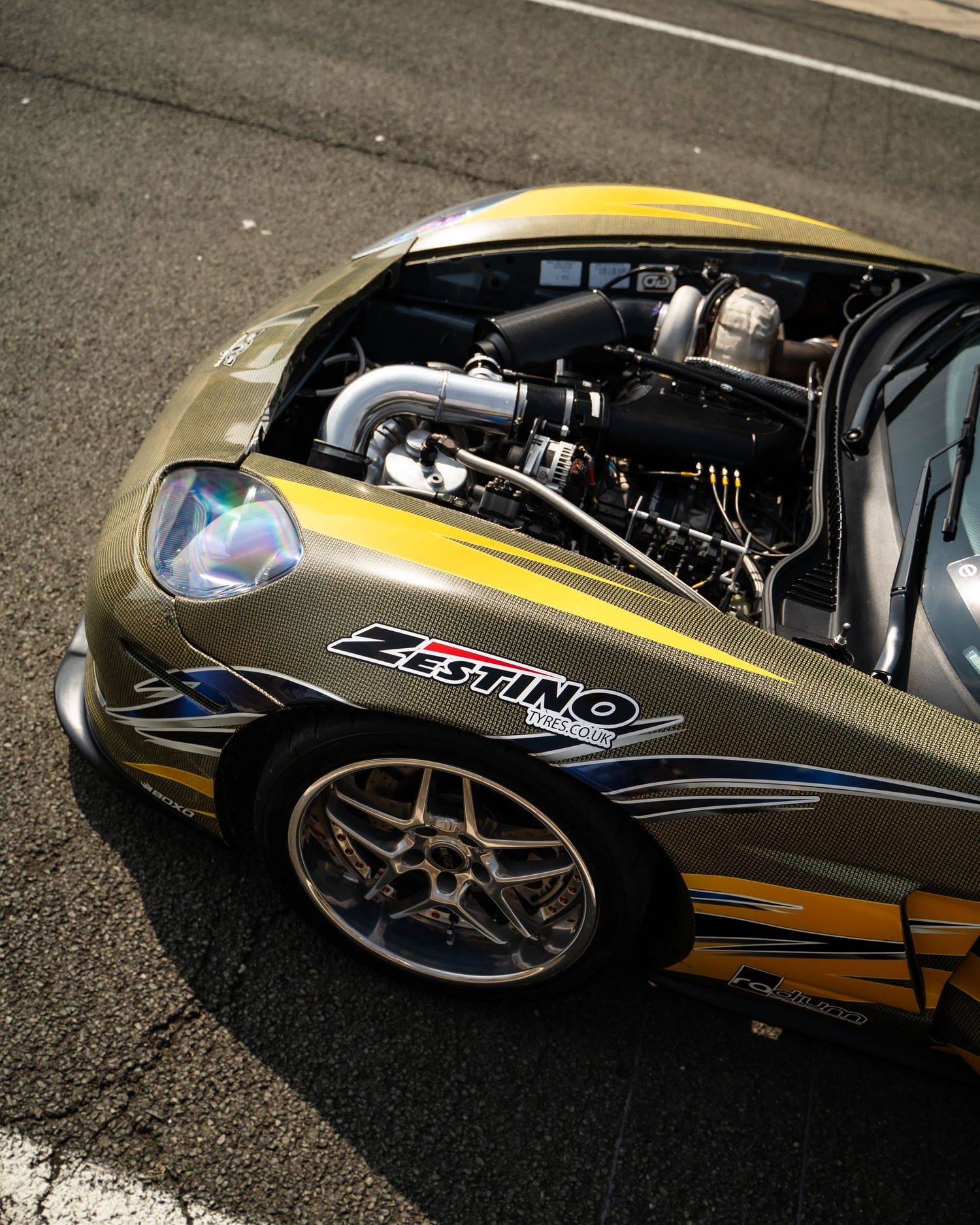 Side view of a custom yellow and black sports car with performance wheels.