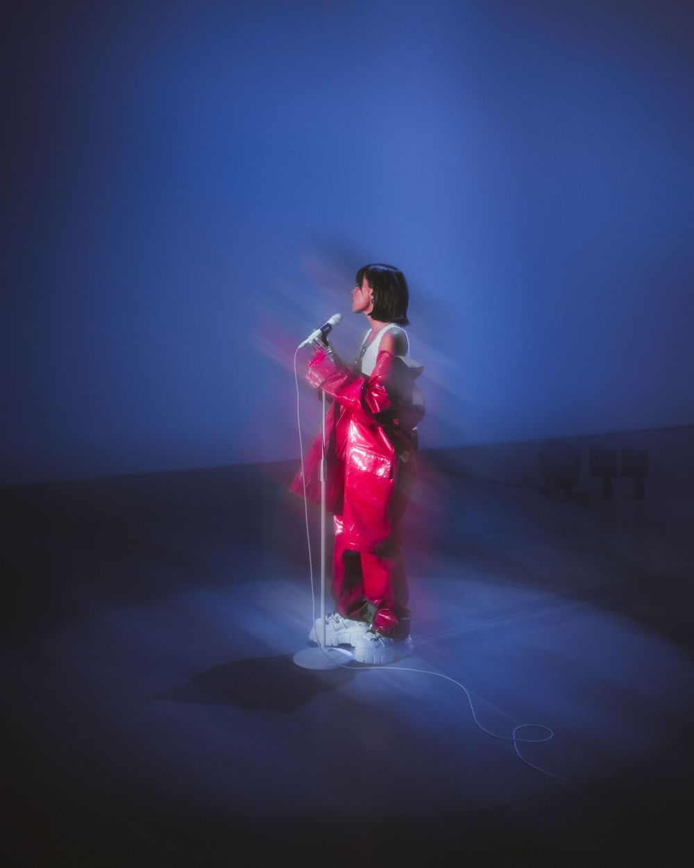 A figure in red winter clothing holds a glowing lantern while standing in deep snow at night with a blue atmospheric backdrop.