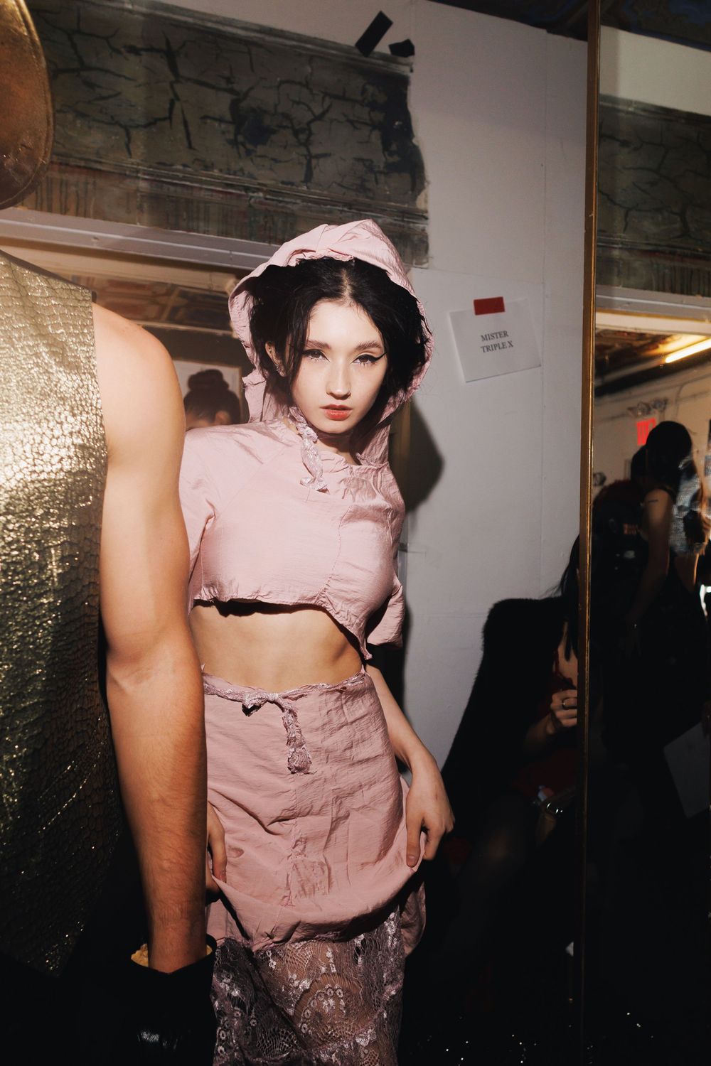Model wearing pink corset top backstage at fashion event.