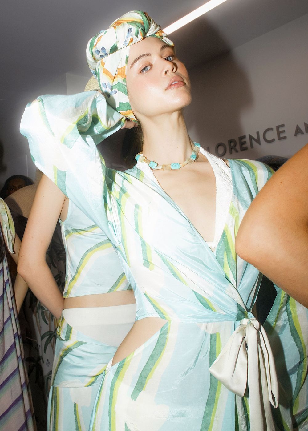 Model in a pastel green floral print dress strikes dynamic poses during a photo session.