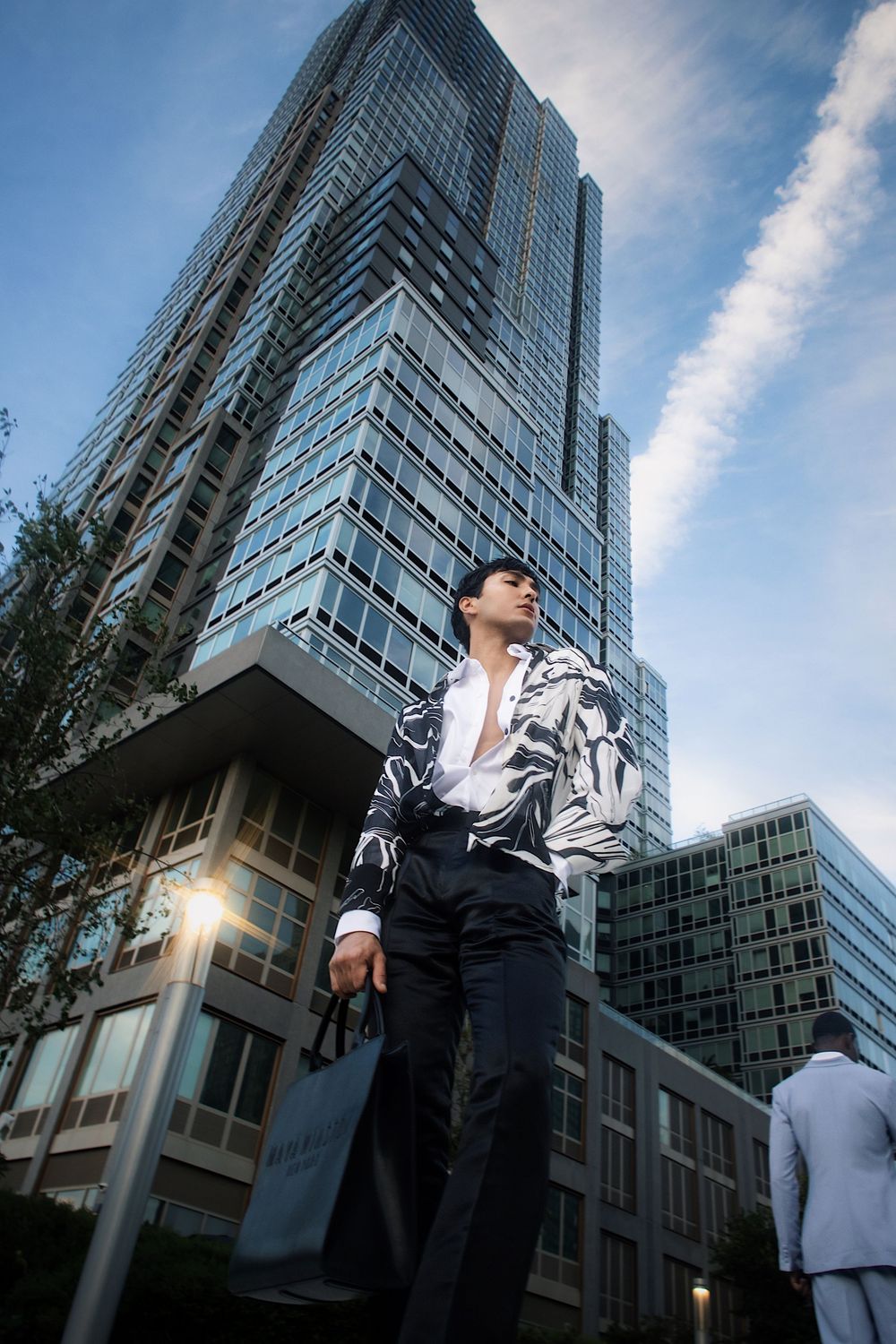 Low angle view of a modern glass skyscraper with a person standing in front of it during daytime.