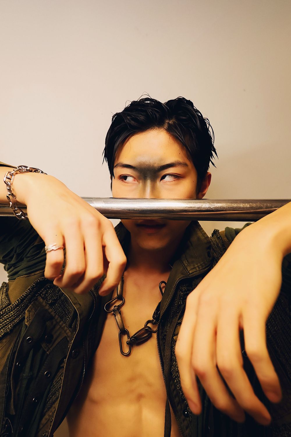 Artistic close-up photo showing hands gripping a metal bar against dark background.