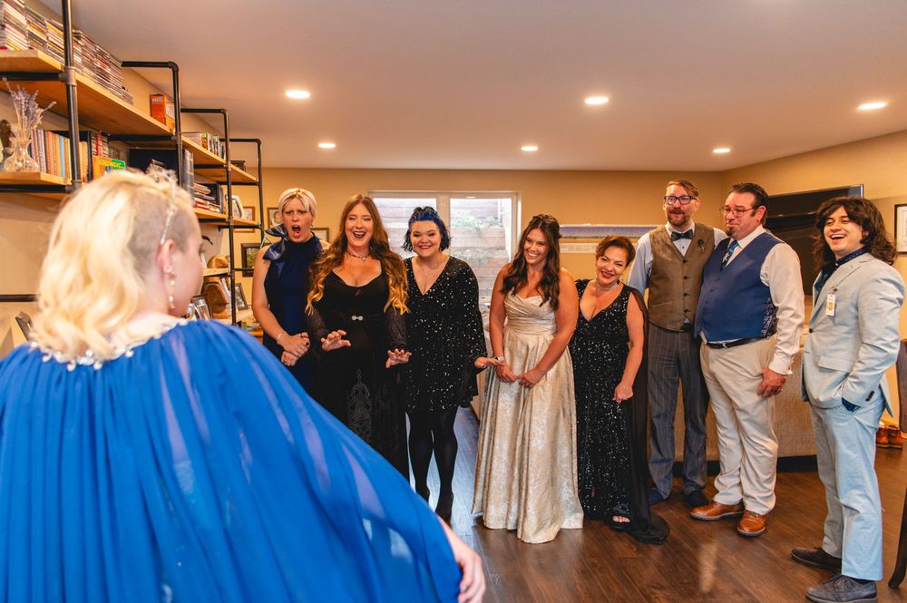 Wedding party gathered in a reception hall wearing various shades of blue and light-colored dresses and suits.