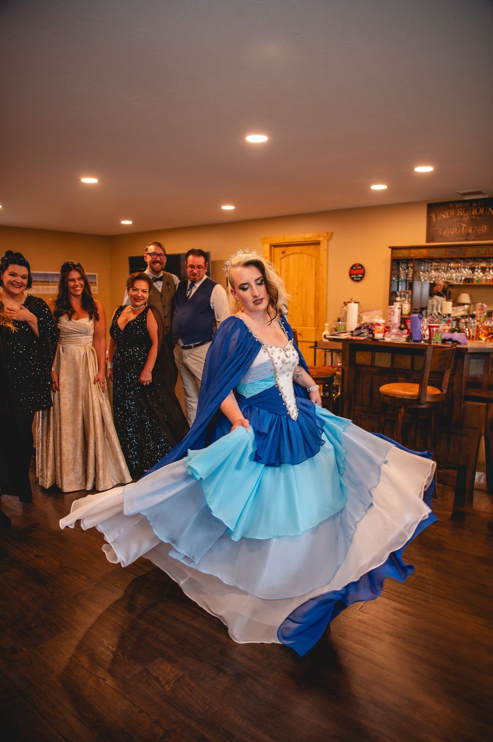 Wedding couple spins across wooden dance floor in blue and white dress with guests watching from the sidelines.