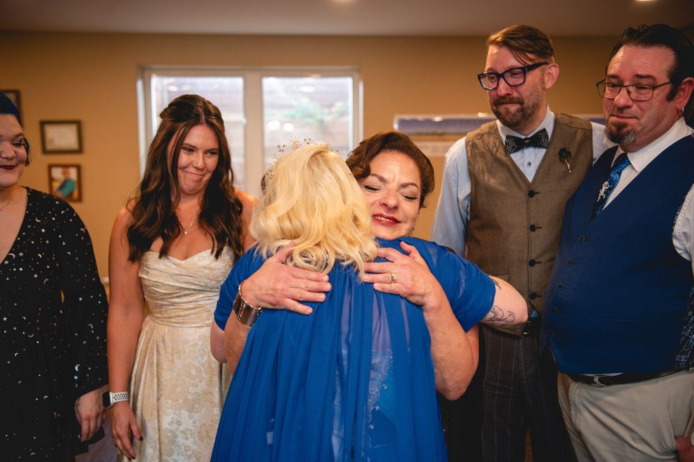 Wedding guests mingling and socializing at a reception while holding drinks and chatting.