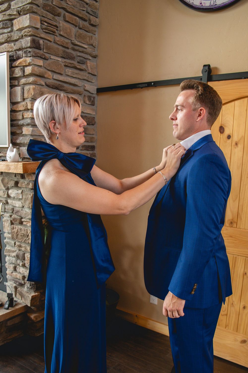 A sequence showing someone in a navy blue suit being helped with adjusting their tie and attire before an event.