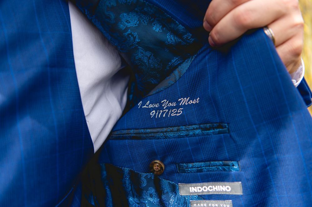 Close-up details of a navy blue suit jacket showing fabric texture, buttons, and labels.