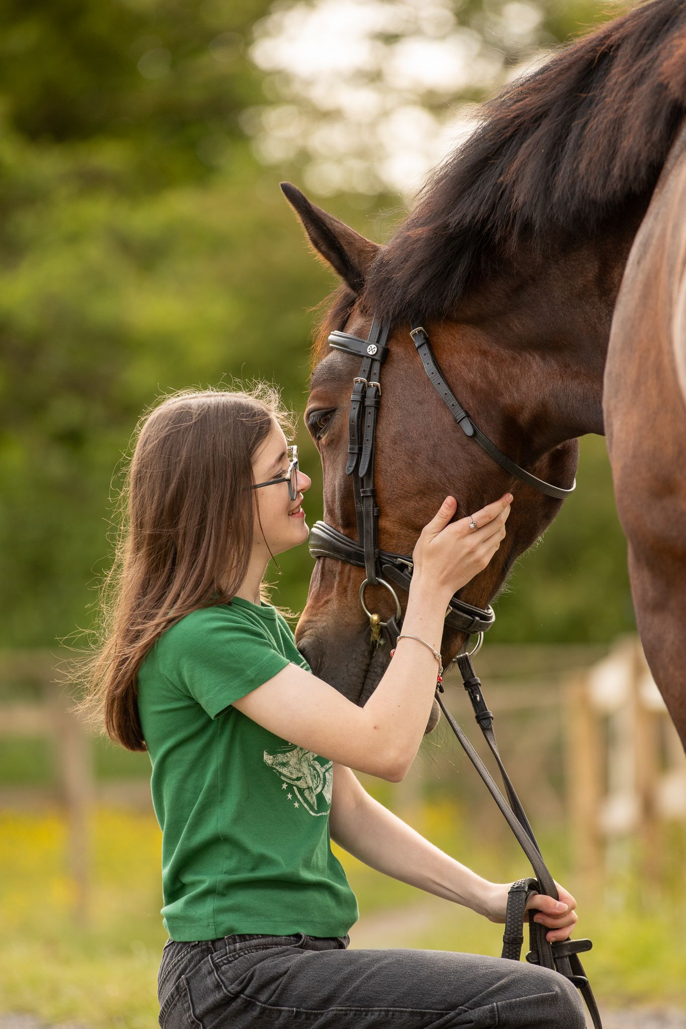 Person in green shirt showing affection to a brown horse outdoors, creating a tender bonding moment.