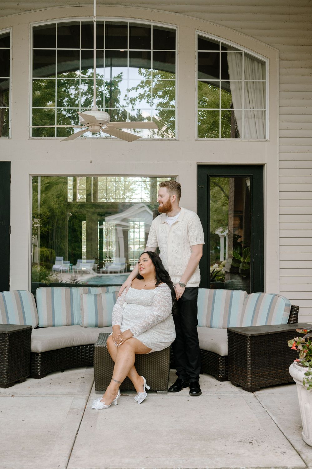 Wedding portraits showing couple in white and black attire on a covered outdoor patio with blue seating.
