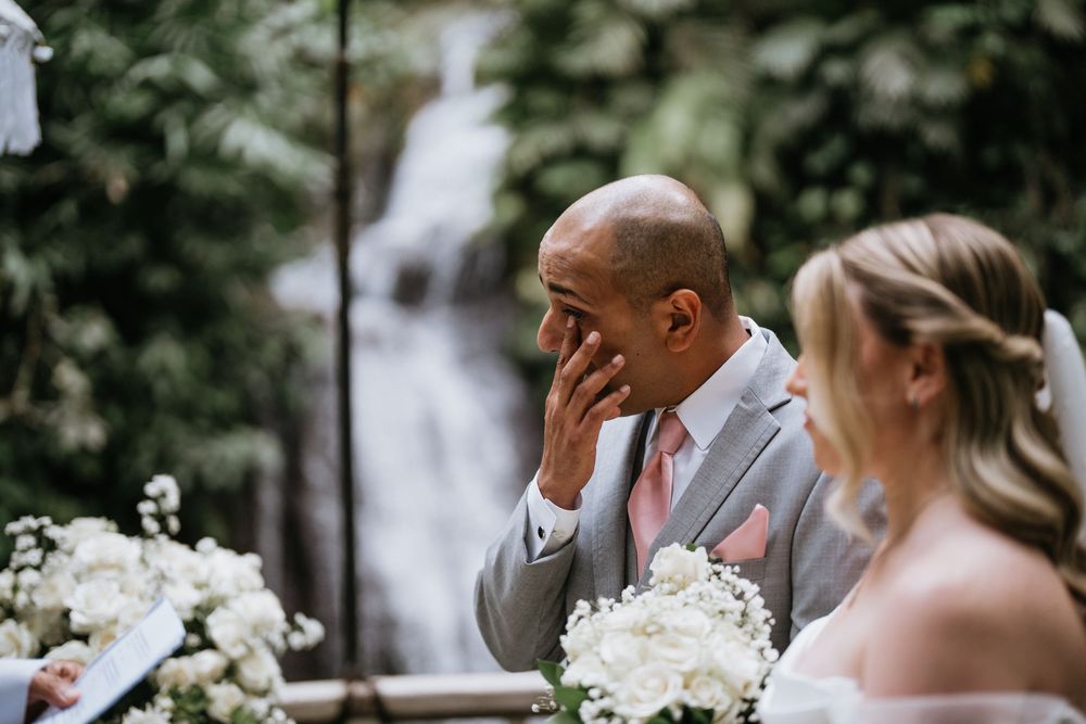 A wedding couple exchanges rings during an outdoor ceremony.