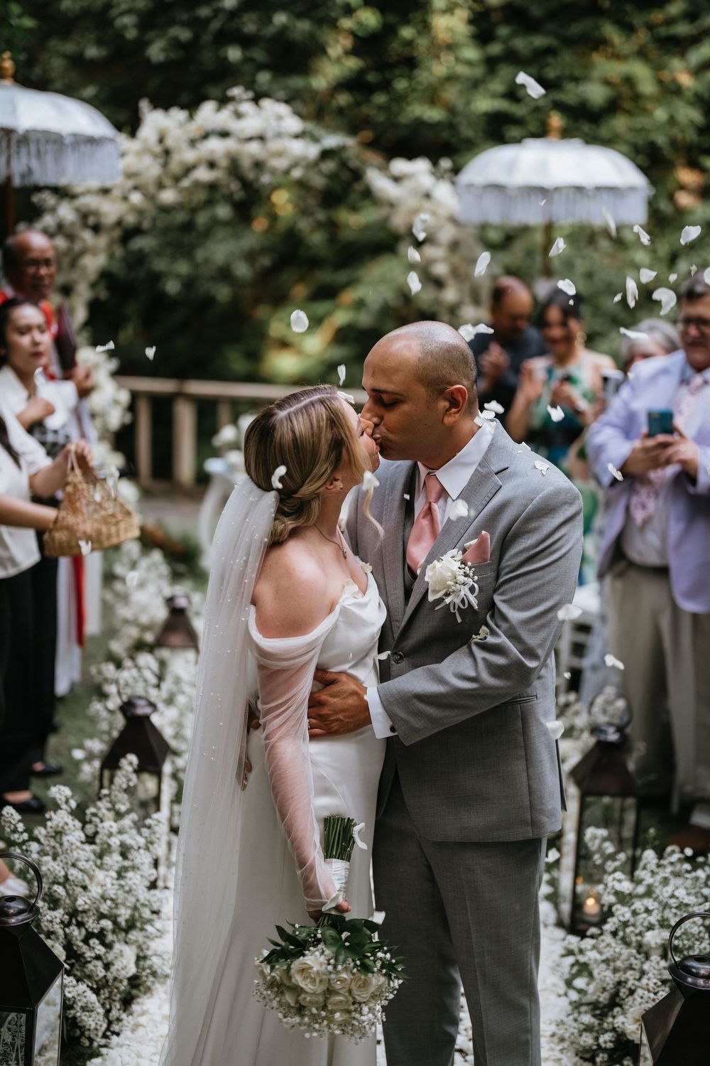 A joyful first dance moment surrounded by white floral decorations and celebrating guests.