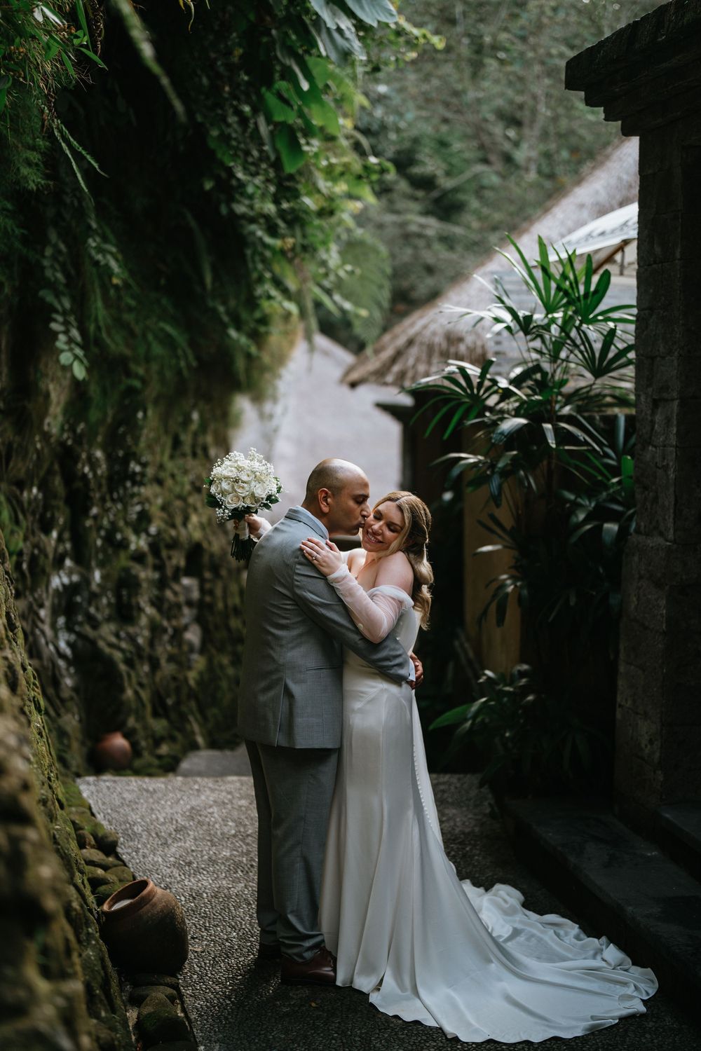 Newlyweds share an intimate moment in front of a waterfall backdrop.