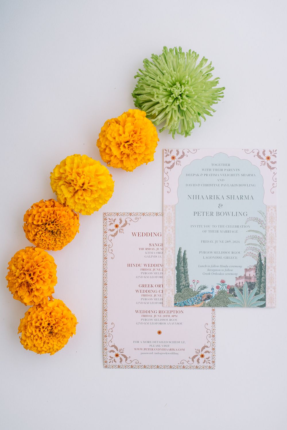 Wedding invitation cards with floral illustrations displayed alongside orange marigolds and a green chrysanthemum flower.