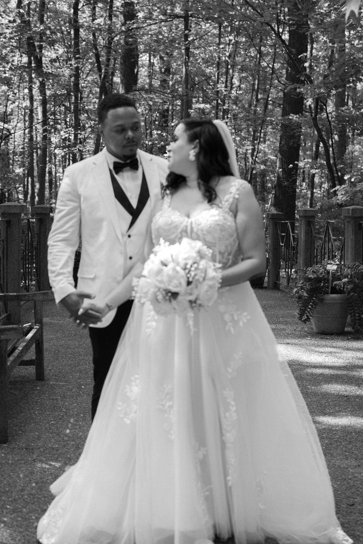 Black and white wedding photo series showing couple in formal attire posing outdoors among trees in romantic forest setting.