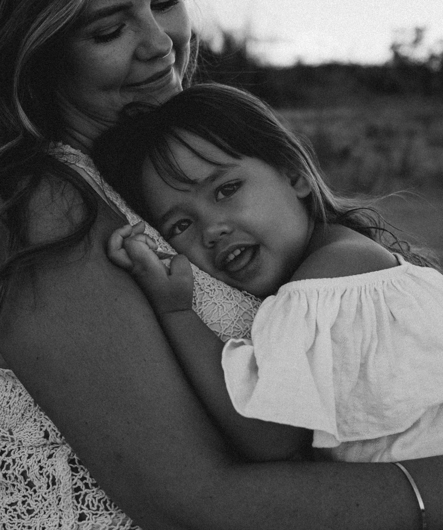 A tender black and white photograph in Denia capturing a warm embrace outdoors in soft natural lighting. Denia family photographer