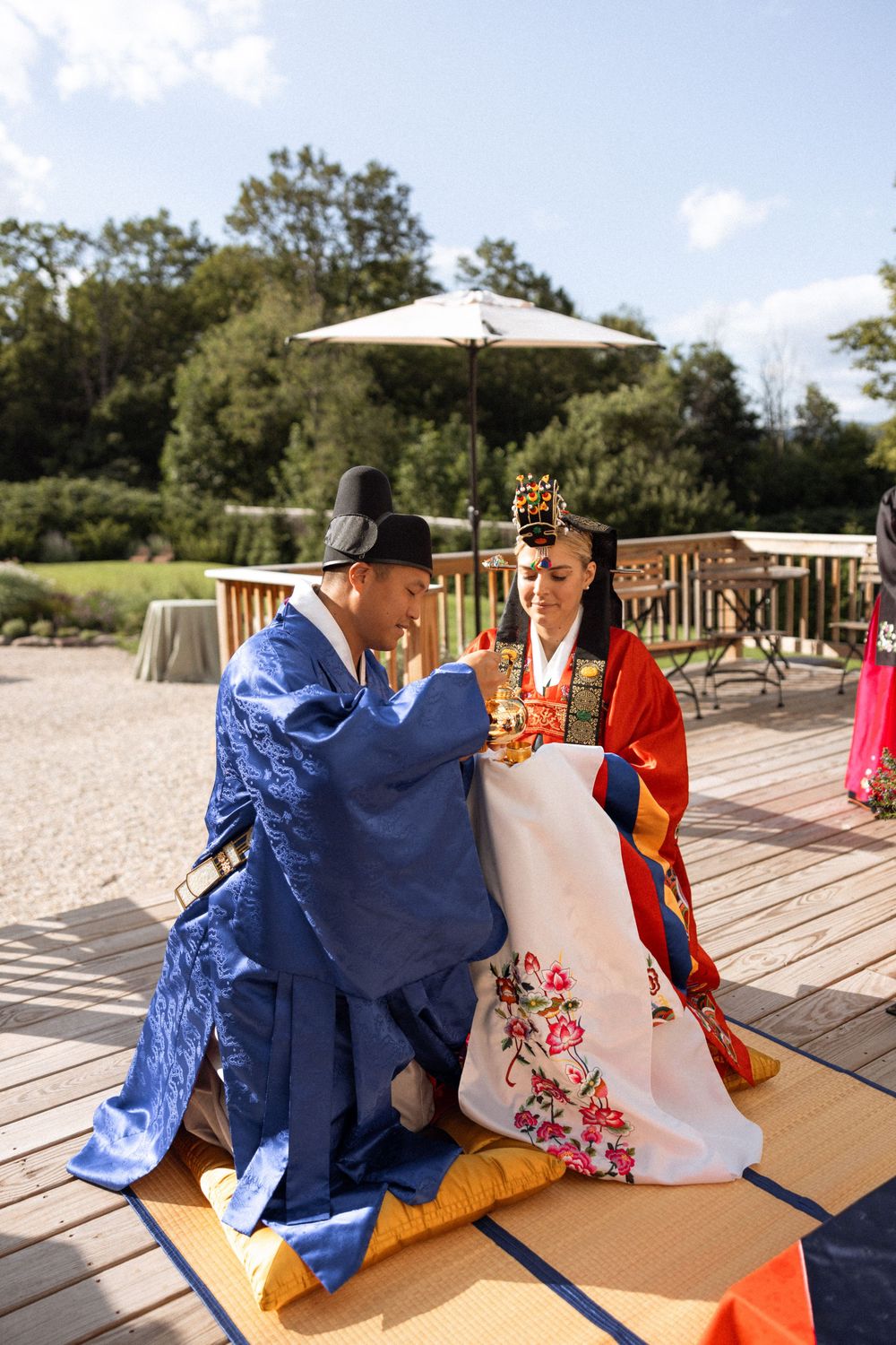 Traditional Korean tea ceremony performed on outdoor deck during wedding celebration.