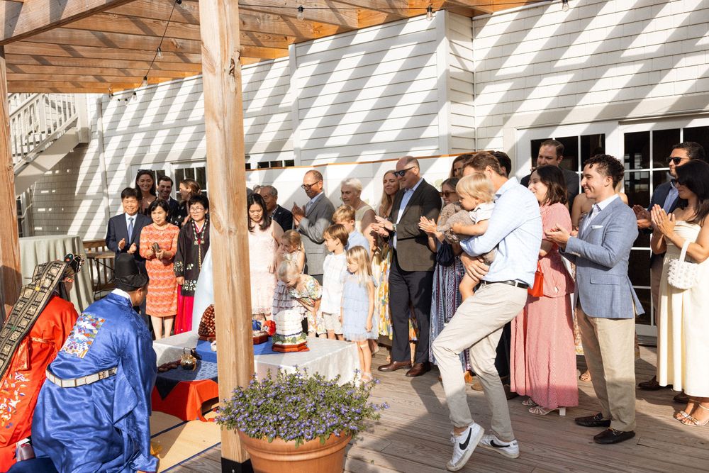 Wedding celebration under covered deck area with guests watching traditional ceremony.