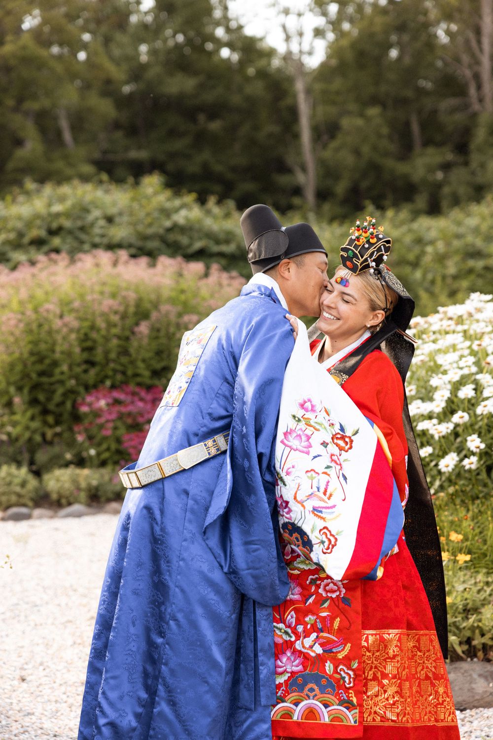 Korean wedding couple sharing intimate moment in garden setting wearing traditional hanbok.