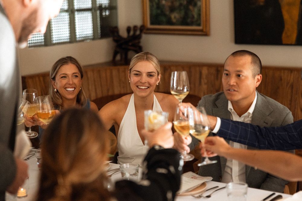Wedding guests toasting with wine glasses at an indoor reception.