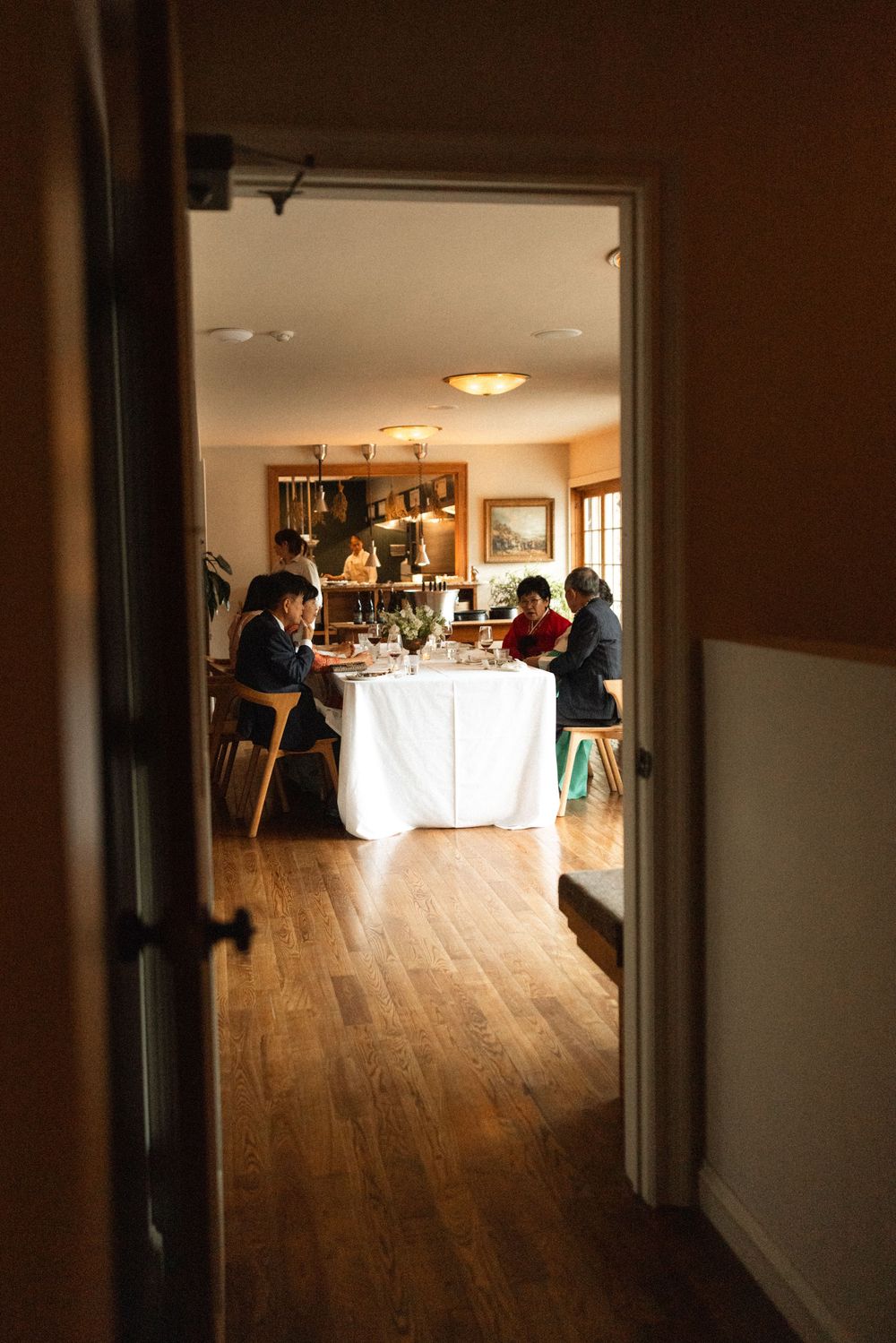 View through doorway of wedding reception dinner with guests seated at tables in a rustic dining room.