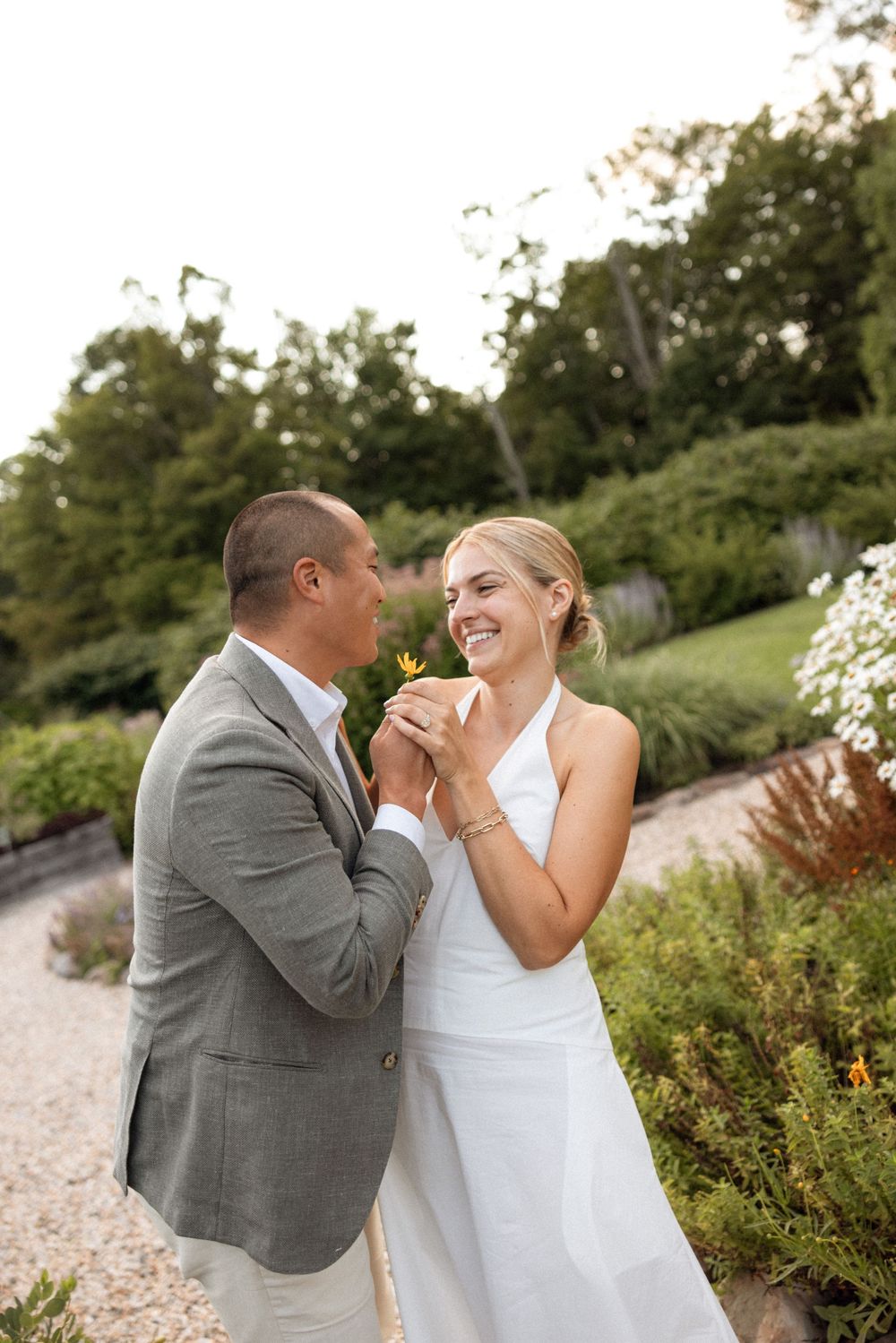 A couple shares a joyful moment together in a garden setting during their wedding celebration.