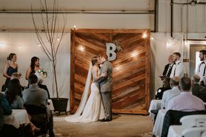 Wedding ceremony in a rustic venue with wooden chevron backdrop and string lights creating an intimate atmosphere.