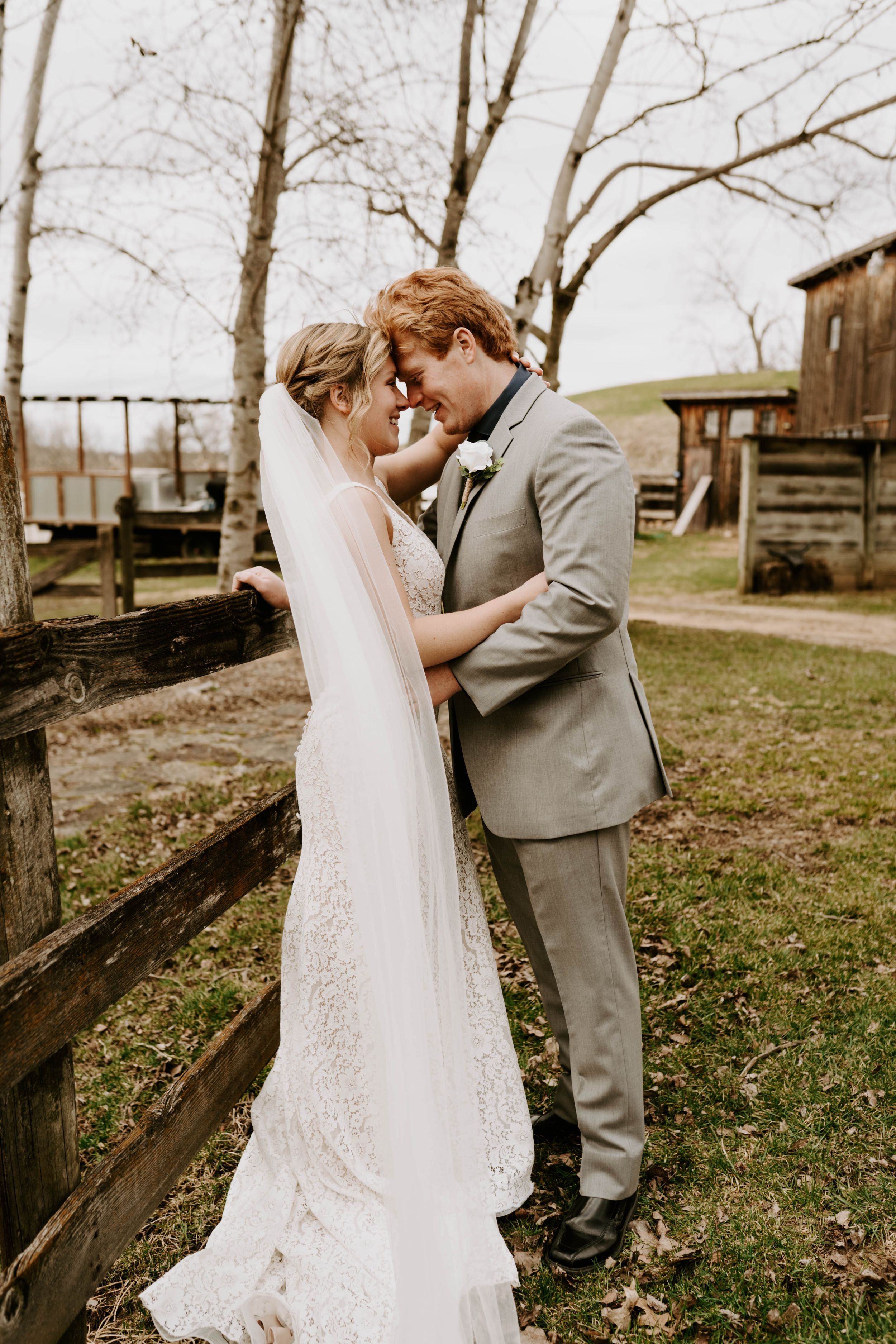 Bride and groom share tender moments during their first look in rustic outdoor setting.