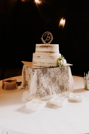 Wedding cake display with delicate lace tablecloth and soft lighting.
