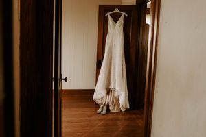 White wedding dress hanging in doorway with natural window light.