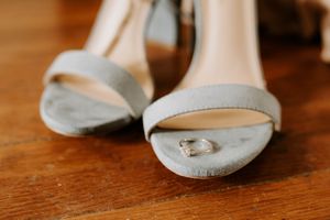 Elegant white bridal shoes on wooden floor detail shot.